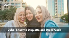 Three women in hijabs smile against Dubai skyline, illustrating local dress etiquette.