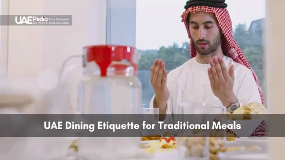 Man in traditional dress praying before meal at a UAE dining table.
