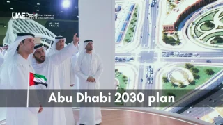 Several men in traditional kanduras are discussing an aerial city planning diagram with an Abu Dhabi 2030 plan label.