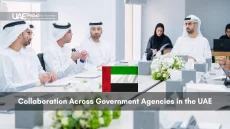 Men and women in Emirati attire seated around a conference table in discussion.