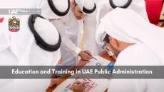 United Arab Emirates emblem next to a group of Emirati officials leaning over documents and pens during a training exercise