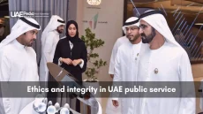 Group of Emirati leaders in kanduras and abaya observing an interactive exhibit on ethics and integrity in public service