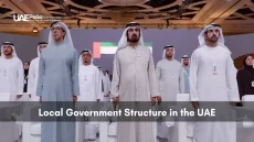 Group of UAE leaders in traditional dress at a formal gathering with the national flag.