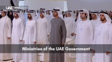 Group of male Emirati ministers and officials standing in rows at a government conference under bright lights