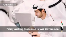 Man in traditional Emirati attire working on a laptop at a government meeting.