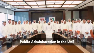 Emirati government officials in traditional dress standing around a large conference table under skylights