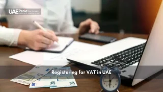 Person working at a desk with documents, money, and laptop
