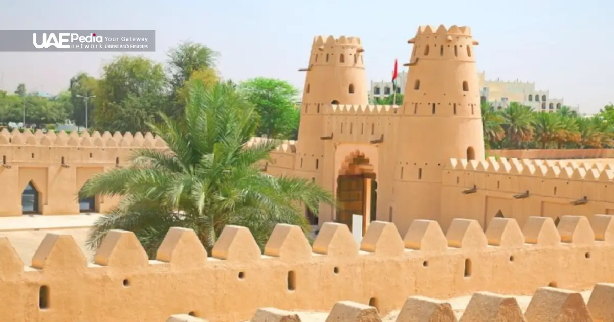 A traditional UAE fort with watchtowers, surrounded by palm trees and greenery.