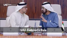 Two men in traditional Emirati dress talking across a conference table.