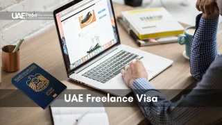 Person using a laptop at a desk with a United Arab Emirates passport and coffee mug nearby