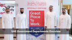 Group of Emirati officials in kanduras standing next to a Great Place to Work certified display by Dubai HR department