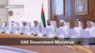 UAE ministers wearing white kanduras at a large conference table with UAE flag and portraits.
