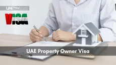 Close-up of hands signing property contract by a house model with a UAE-flaged VISA logo above it
