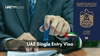 Hand holding a blue stamp over a visa form with a United Arab Emirates passport shown nearby.