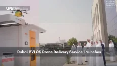 Officials observe the launch of a drone delivery pod outside a modern building