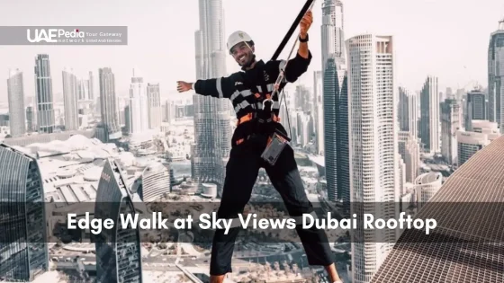Participant in safety harness leans out over Sky Views rooftop with Burj Khalifa view.