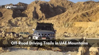 Silver and beige off-road vehicles navigating uneven desert mountain terrain under clear sky