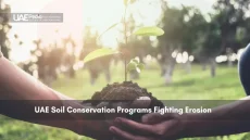 Hands holding a small plant with soil, symbolizing soil conservation.