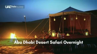 Bedouin-style tent illuminated by hanging lanterns next to a glowing bonfire on desert dunes.