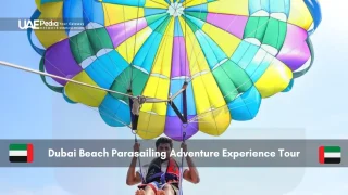 Man parasailing over Dubai beach under colorful parachute