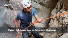 Man climbing in rocky terrain with rope and helmet