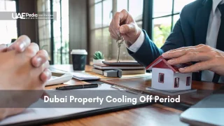 Person in business attire giving house keys beside a small property model, showing ownership transfer.