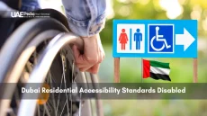 Hand on wheelchair wheel next to an accessibility and restroom directional sign in Dubai.