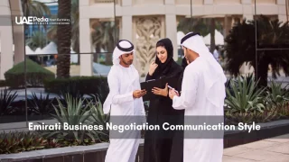Three Emirati businesspeople in traditional dress review documents outside an office plaza.