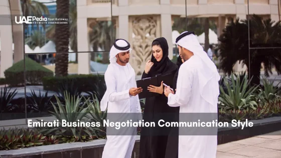 Three Emirati businesspeople in traditional dress review documents outside an office plaza.