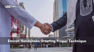 Close-up of two Emirati men performing a traditional handshake greeting in a Dubai urban environment.