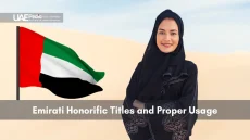 Confident Emirati woman in abaya beside waving UAE flag in desert.