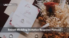Wedding invitation cards, rings and dried flowers arranged to show Emirati RSVP protocol.
