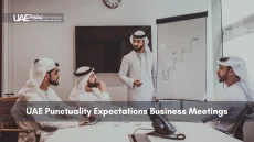 Group of UAE businessmen in traditional dress discussing strategy beside a whiteboard.