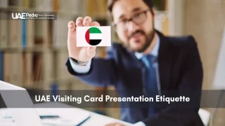 Man in suit holds a business card with a UAE flag icon against a blurred office backdrop.