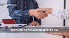 Businesspeople shaking hands over property documents and a model house.