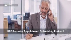 A man in a suit takes notes while on a call, arranging a business meeting.