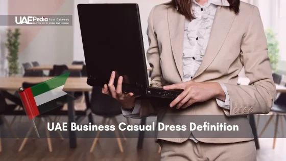 A woman dressed in a beige blazer and white blouse holding a laptop, representing business casual attire in the UAE.